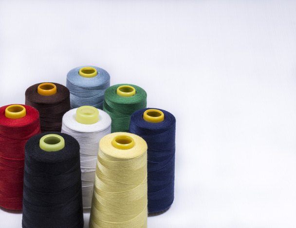 buntes Sortiment lebhafter Farben von Baumwollspulen auf Zapfen für den Einsatz in der Strickwaren- und Bekleidungsindustrie aus der Vogelperspektive - Foto, Bild