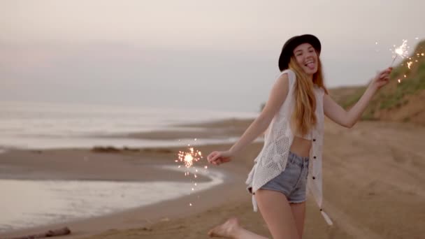 Prachtige tienermeisje met wonderkaarsen op het strand bij zonsondergang - Video