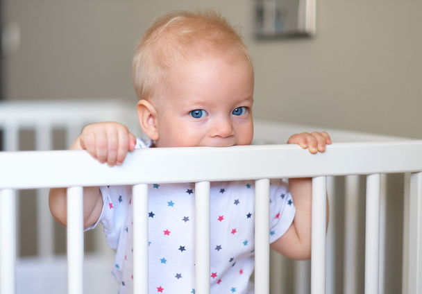 Baby standing in crib - Foto, afbeelding