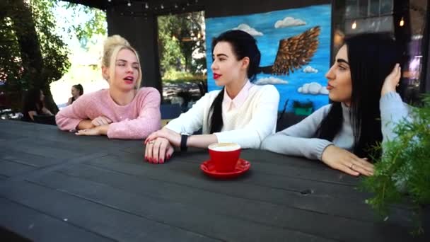 Drie mooie vrouwelijke glimlach in Cafe, praten, vertellen geheimen, eten, koffie drinken. - Video