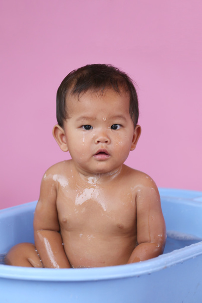 Азиатский ребенок купается в голубом бассейне с радостью
. - Фото, изображение