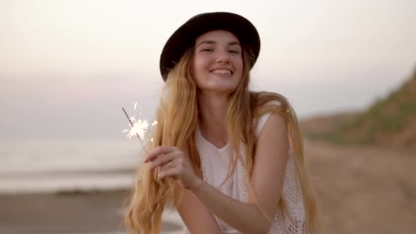 Teenage krásnou dívku s prskavky na pláži při západu slunce - Záběry, video