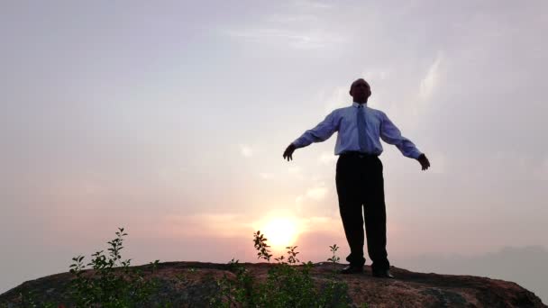   Zakenman (gebed) mediteert boven op de berg bij rode zonsopgang. 4k 3840 x 2160 - Video