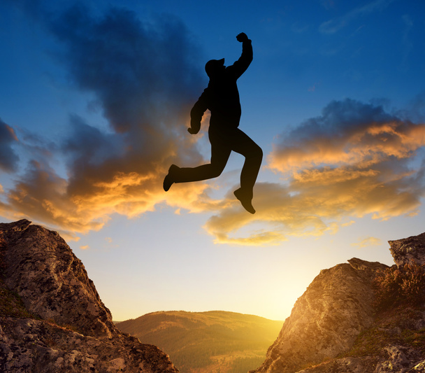Silueta turista saltando sobre la brecha
 - Foto, Imagen