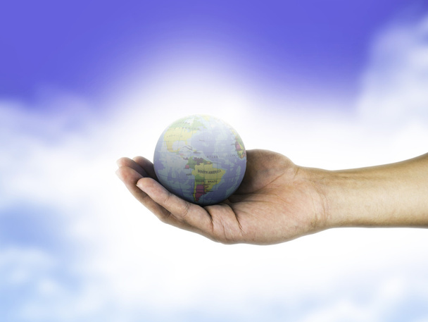 Globus in der Hand hält auf blauem Himmel Hintergrund - Foto, Bild