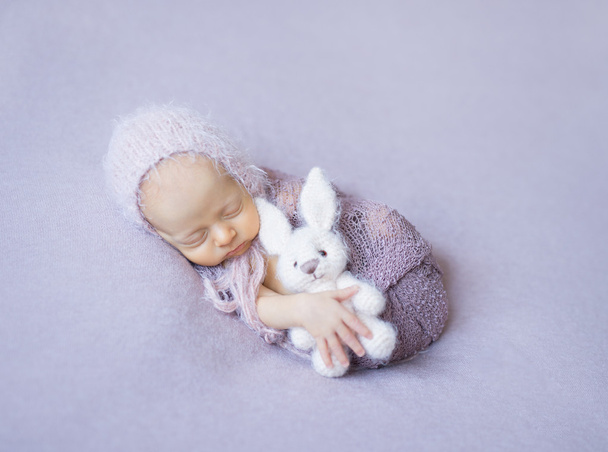 swaddled sleeping newborn with toy in hand - Фото, изображение