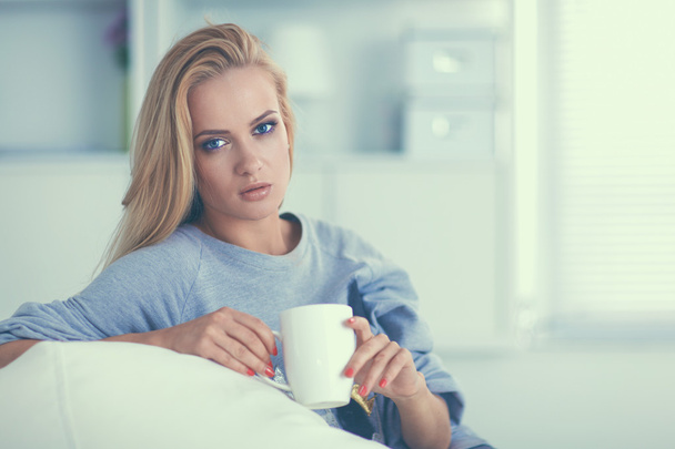 Woman sitting on the couch with cup in her hands - Photo, Image