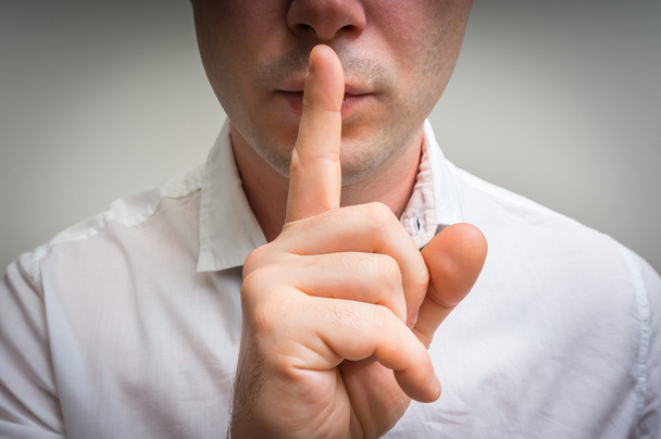 Homme attrayant avec doigt sur les lèvres faisant un geste de silence
 - Photo, image