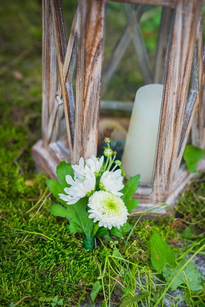 the wedding boutonniere for the groom made of white and green chrysanthemum  Vintage wooden lantern and moss on the background and a candle  - Photo, Image