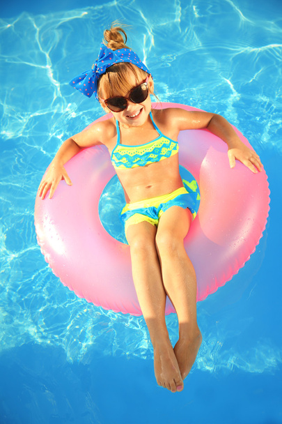 Meisje in zwembad op een zonnige dag - Foto, afbeelding