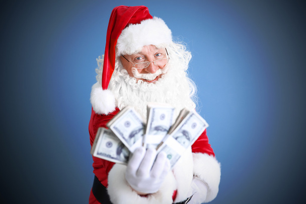 Santa Claus holding money on blue background - Foto, Imagen