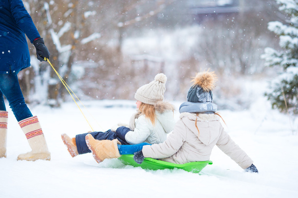 Little girls enjoying sledding in winter day. Father sledding his little adorable daughters. Family vacation on Christmas eve outdoors - Photo, Image