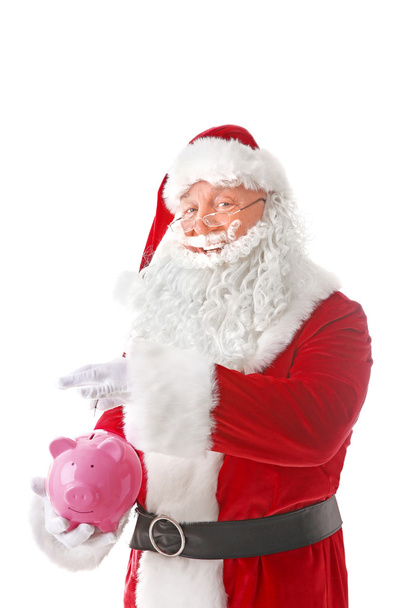 Santa Claus putting coin into piggy bank on white background - Фото, зображення