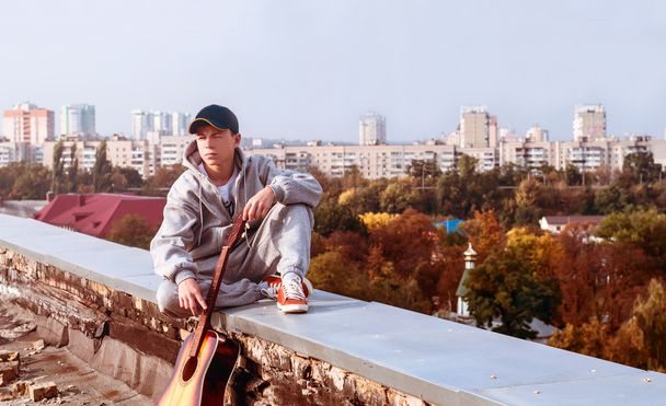 jonge man op het dak met een gitaar - Foto, afbeelding