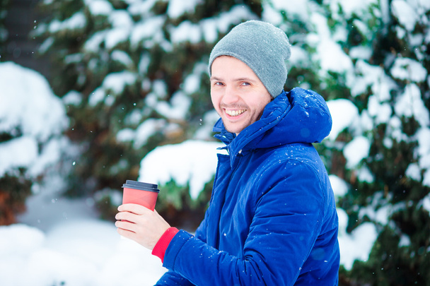 Kaukázusi fiatalember, forró kávét iszik a fagyasztott téli nap a szabadban - Fotó, kép