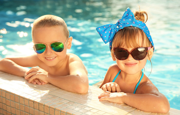 Little kids in swimming pool on sunny day - Фото, изображение
