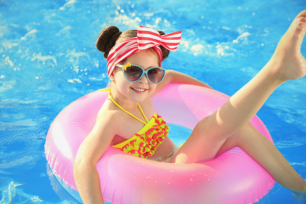 Little girl in swimming pool on sunny day - Fotó, kép