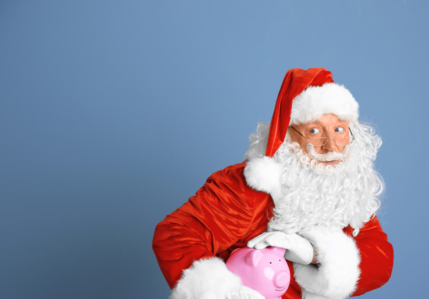 Santa Claus drží prasátko na modrém podkladu - Fotografie, Obrázek