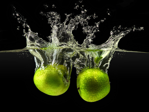 Group of green apples falling in water on black - Photo, Image