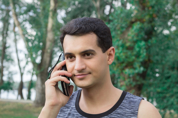 Nuori kunto mies puhuu matkapuhelimella harjoittelun aikana
 - Valokuva, kuva
