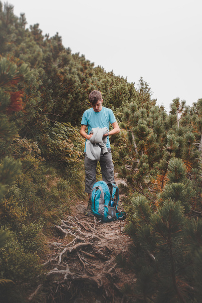 Boy packing his clothes to backpack on trail - Foto, afbeelding