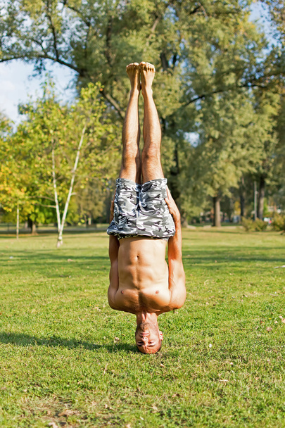 Young Athlete Standing on Head in in the Park. Street Workout. - 写真・画像