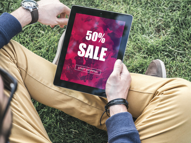 Jonge hipster man met zijn moderne digitale tablet koop online winkelen, koop goedkope promotie - Foto, afbeelding