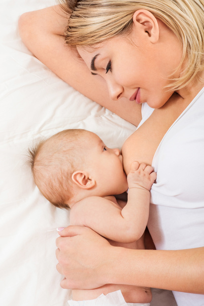 Young mother breastfeeds her baby - Foto, afbeelding
