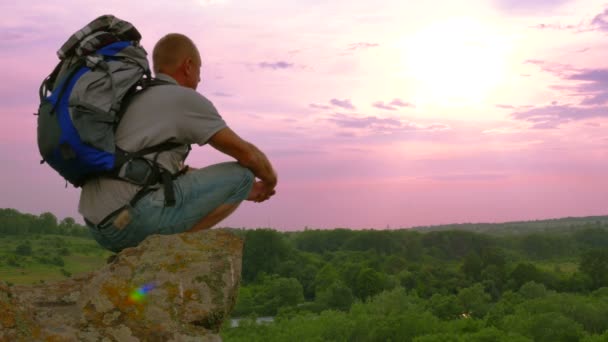   Turistické dospělý muž s batohem na vrchol hory se dívá na západ slunce 4k 3840 x 2160 - Záběry, video