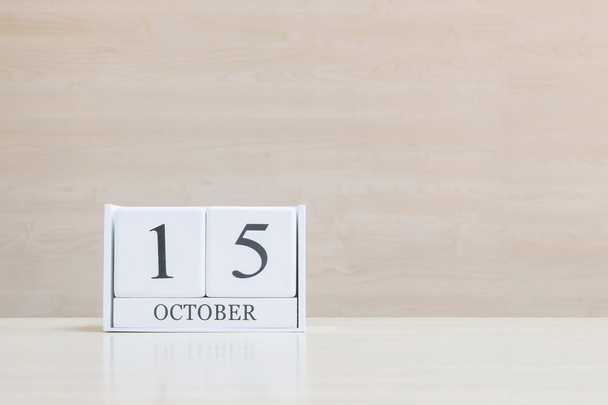 Closeup surface white wooden calendar with black 15 october word on blurred brown wood desk and wood wall textured background with copy space , view another more date in my portfolio - Photo, Image
