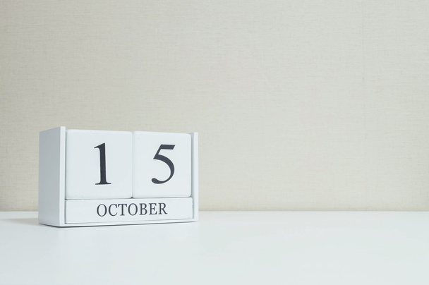 Closeup white wooden calendar with black 15 october word on blurred white wood desk and cream color wallpaper in room textured background with copy space , view another more date in my portfolio - Photo, Image