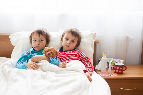 Two sick boys, brothers, lying down in bed with fever - Fotoğraf, Görsel
