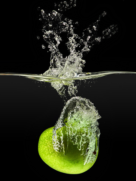 Green apple falling in water on black background - Foto, Imagen