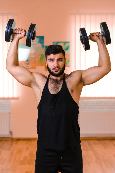 Handsome young muscular man exercising with dumbbells. - Φωτογραφία, εικόνα