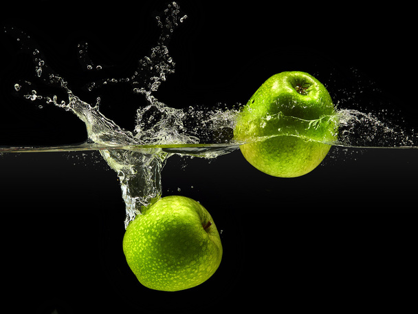 Group of green apples falling in water on black - Foto, immagini