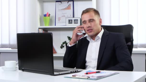 Businessman talking on the phone and writes information - Materiał filmowy, wideo