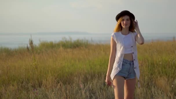 Mladý krásný model v klobouku pózuje na okraji útesu nedaleko řeky - Záběry, video