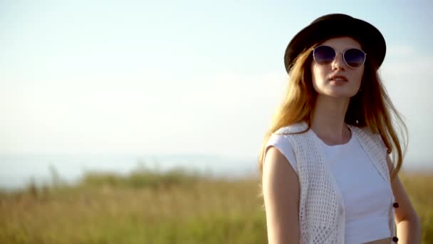 Joven hermosa mujer modelo en sombrero y gafas de sol posando en cámara lenta al aire libre
 - Imágenes, Vídeo