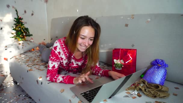 junges Mädchen Porträt Lächeln verwenden Laptop für Online-Shopping mit Kreditkarte Weihnachtsbaum Bokeh Weihnachtsbeleuchtung Neujahr Konfetti Hintergrund zu Hause - Filmmaterial, Video