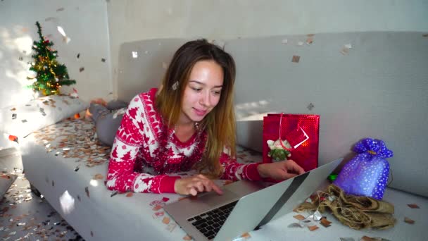 junges Mädchen Porträt Lächeln verwenden Laptop für Online-Shopping mit Kreditkarte Weihnachtsbaum Bokeh Weihnachtsbeleuchtung Neujahr Konfetti Hintergrund zu Hause - Filmmaterial, Video