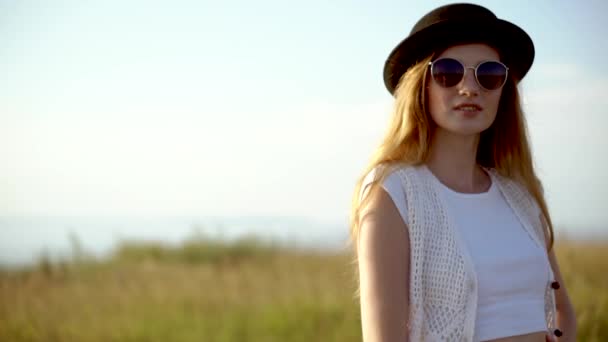 Молода красива жінка модель в капелюсі і сонцезахисних окулярах позує на відкритому повітрі повільний рух
 - Кадри, відео