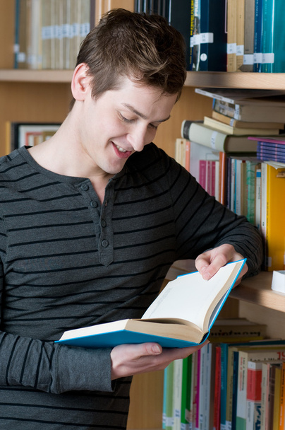 Happy student reading book in a library - Φωτογραφία, εικόνα