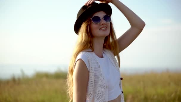Nuori kaunis nainen malli hattu ja aurinkolasit aiheuttaa ulkona hidastettuna
 - Materiaali, video