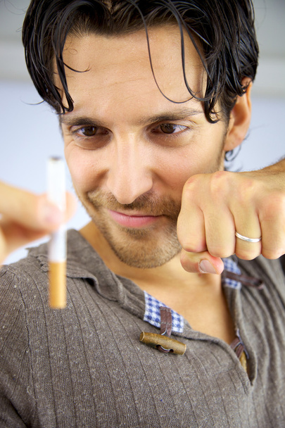Good looking man smiling at cigarette ready to stop smoking - Zdjęcie, obraz