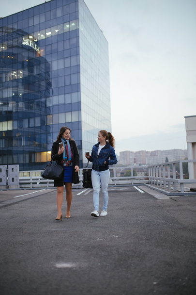 Two modern women friends walking in city and communicating - Foto, Imagem