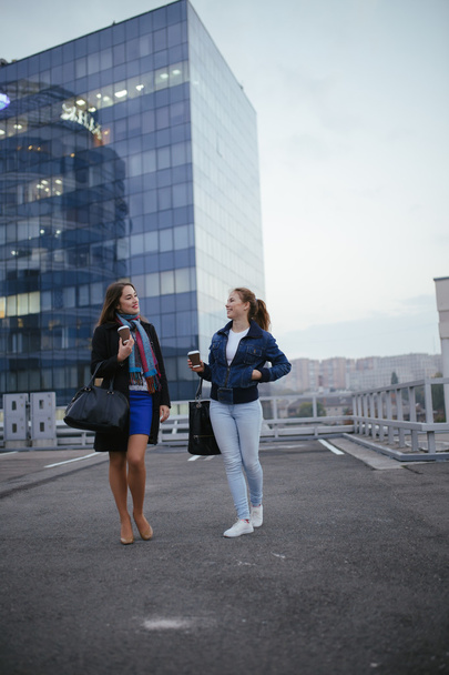 Two modern women friends walking in downtown and communicating - Fotoğraf, Görsel