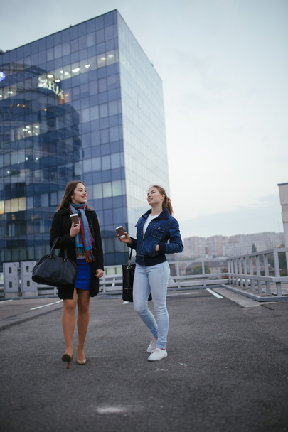 Two modern women friends walking in city and communicating - Fotoğraf, Görsel