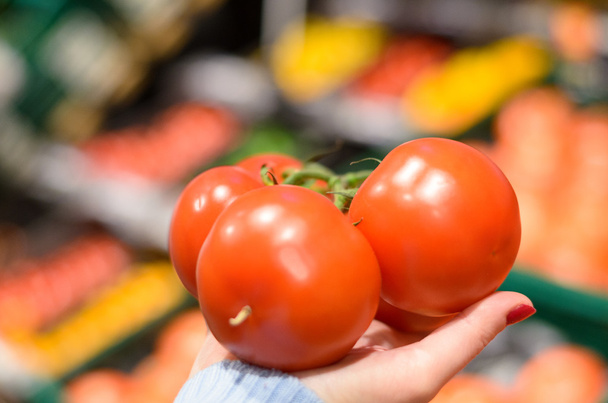 Woman holding three tomatoes at market - Photo, image