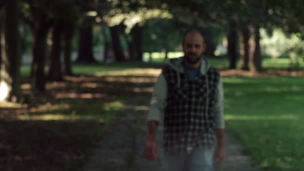  bald man walking in the park at the camera, stop crosses his arms and smiles  - Πλάνα, βίντεο