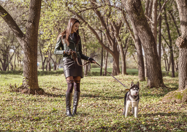 A girl walks with a dog in the autumn. - Фото, зображення